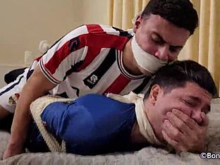Two gay footballers are tied up and gagged in this BDSM scene.